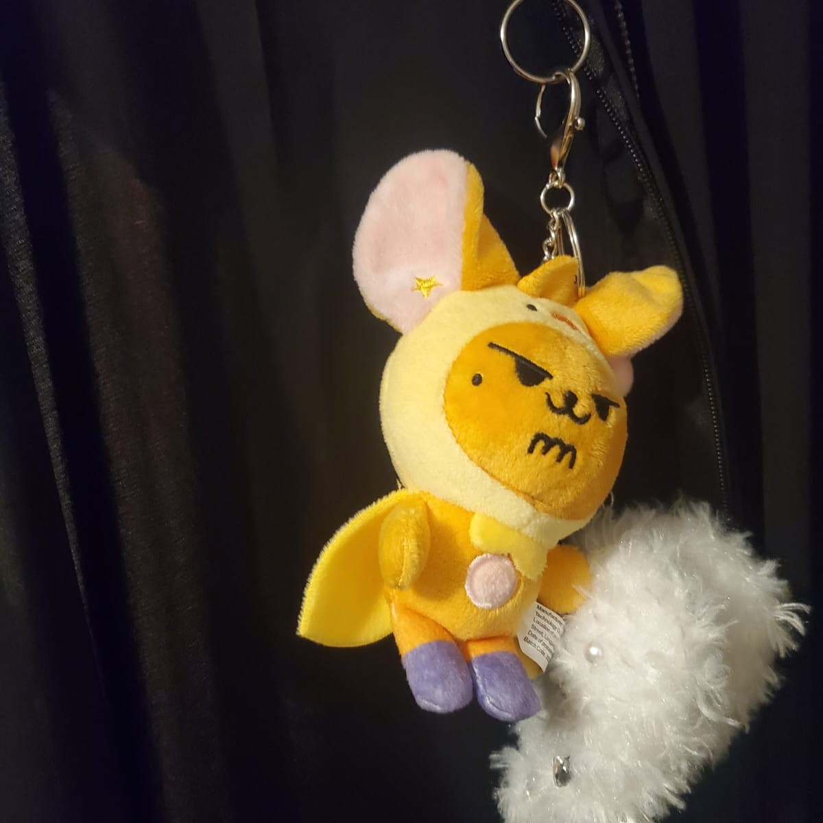 A soft plush keychain hanging from a surface, suggesting touch and movement.